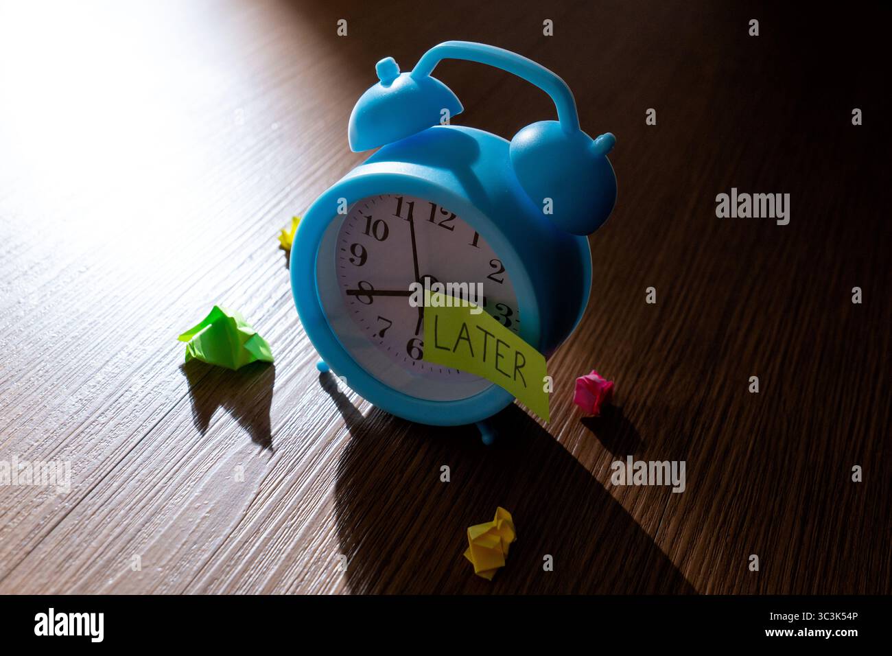 Ein Vintage-Wecker vor dunklem Hintergrund mit einer Notiz „SPÄTER“. Prokrastination, Verzögerung und vergessenes Aufgabenkonzept. Stockfoto