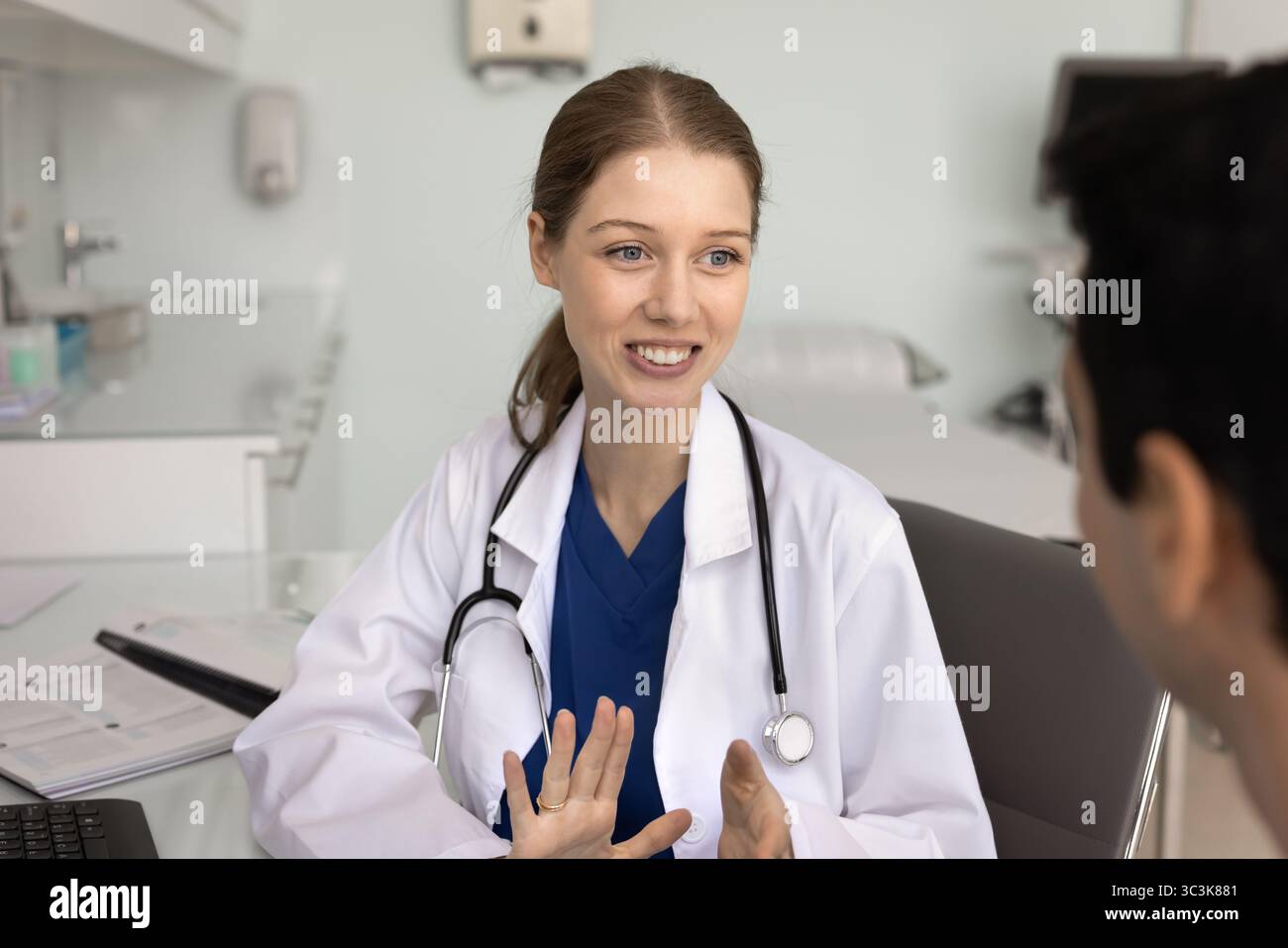 Glückliche junge Ärztin, die mit männlichen Patienten spricht Stockfoto