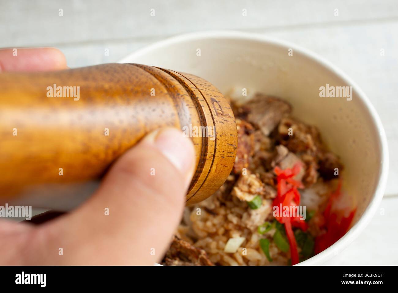 Eine Nahaufnahme der Hände mit einem Pfeffermühle auf einer Hauptspeise. Stockfoto