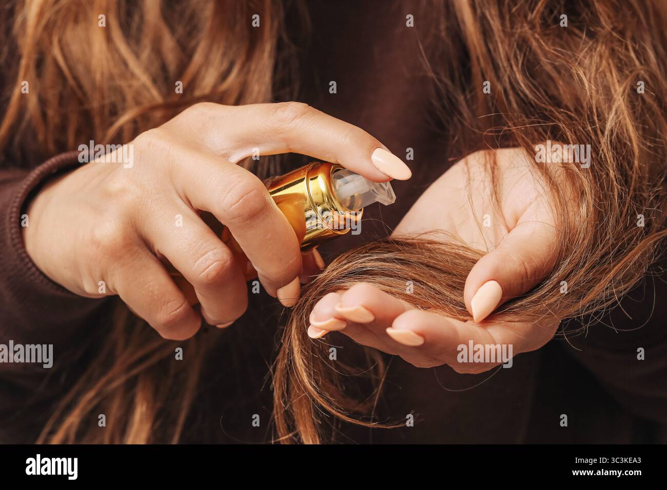 Frau, die Haarserum aufträgt. Hände mit Ölbehandlung. Routinekonzept der Haarpflege. Langes gesundes braunes Haar. Naturschönheitsritual. Feuchtigkeitsspendendes Haar. Stockfoto