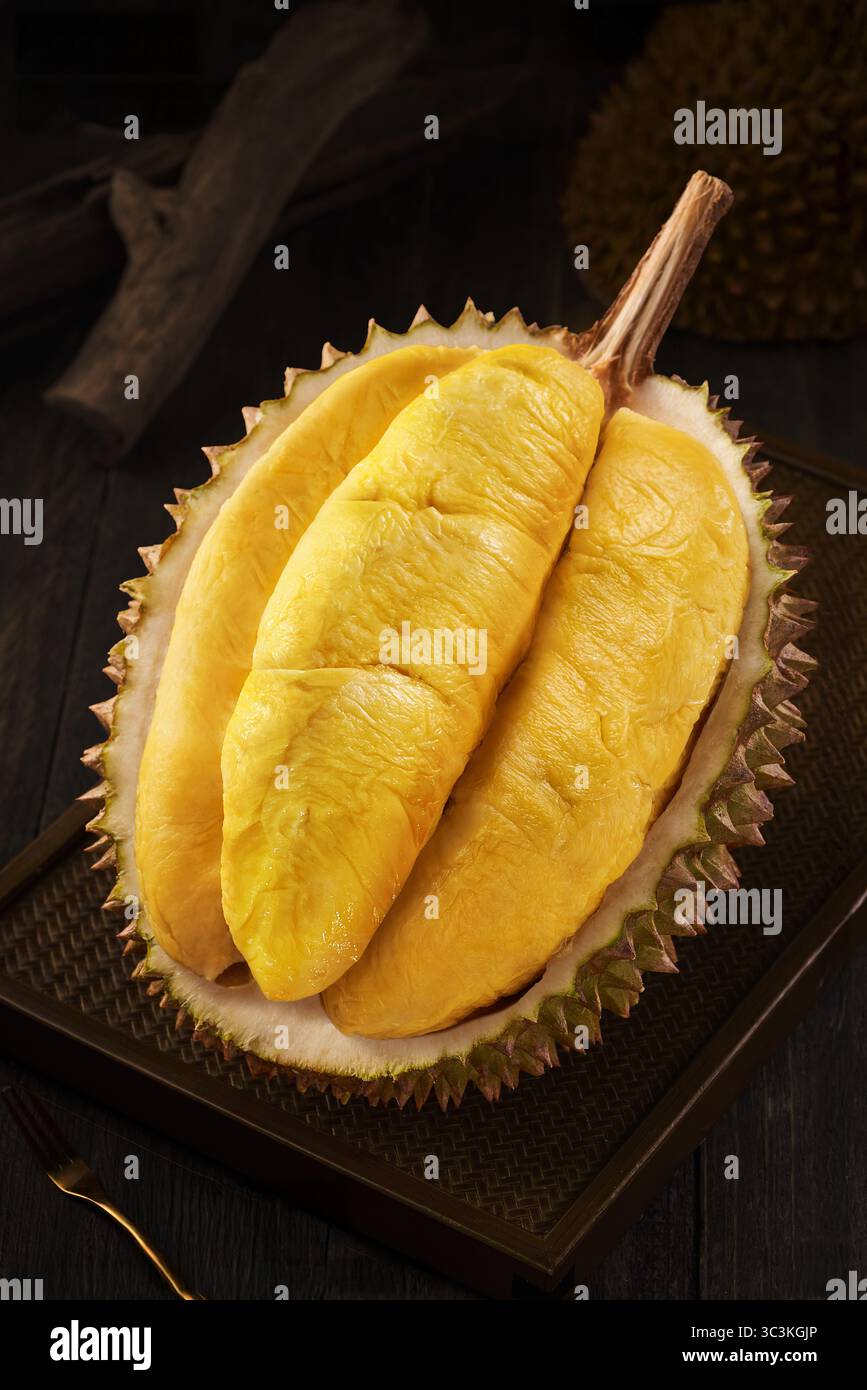 Bild von Durian, köstlichem und frischem vietnamesischem Durian, Durian Fruit Open mit goldenem Fleisch auf dunklem Holztablett Stockfoto