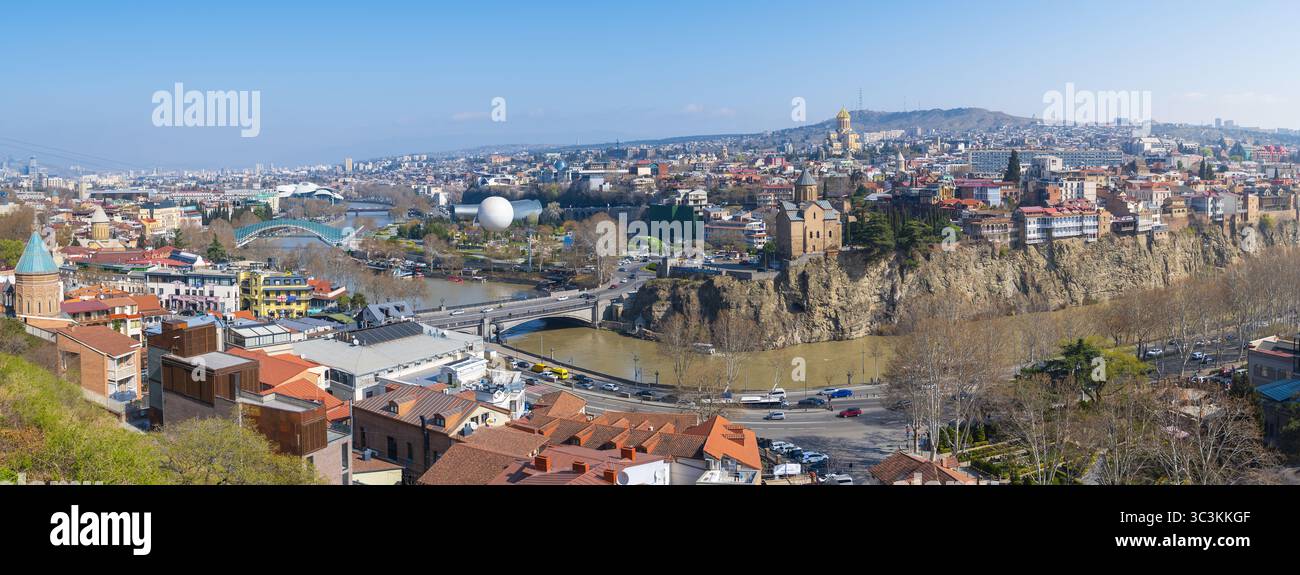 Ein atemberaubender Panoramablick fängt das pulsierende Stadtbild von Tiflis, Georgien, unter einem hellen, klaren Himmel ein. Die historische Architektur und moderne Bauten Stockfoto