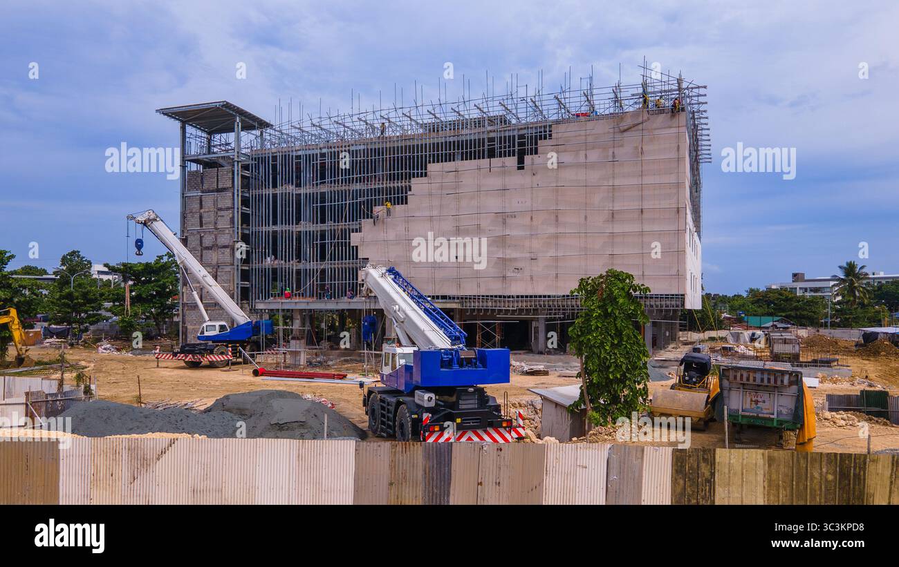 Ein mehrstöckiges Gebäude im Bau mit freiliegenden Stahlrahmen und Gerüsten. Fassadenarbeiten sind als Baumaschinen im Gange Stockfoto