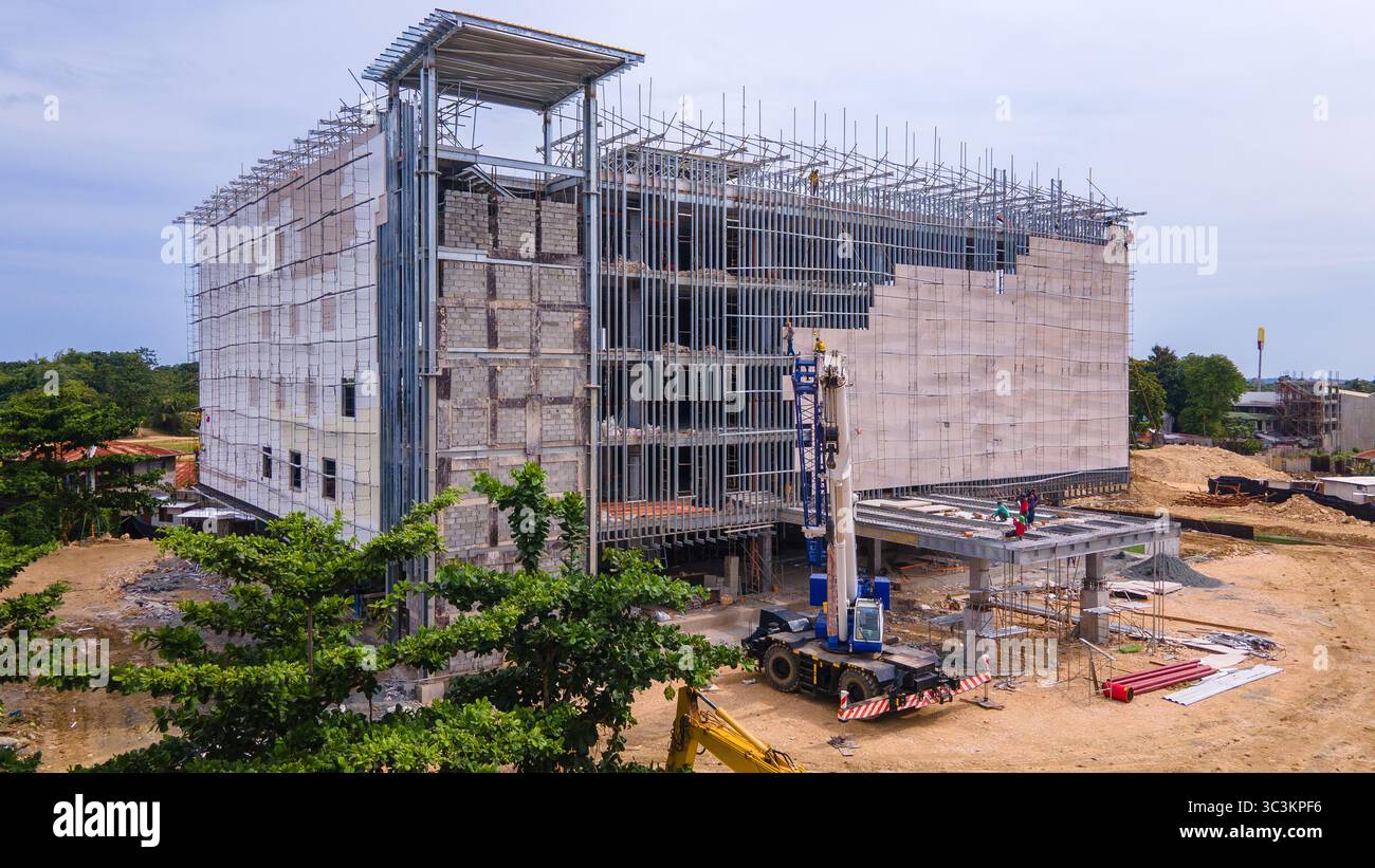Ein mehrstöckiges Gebäude im Bau mit freiliegenden Stahlrahmen und Gerüsten. Fassadenarbeiten sind als Baumaschinen im Gange Stockfoto