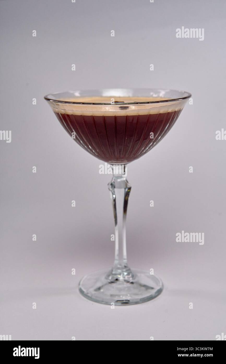 Ein atemberaubender Cocktail in einem eleganten Glas mit satten dunklen Farbtönen und einer cremigen Schaumschicht, perfekt für anspruchsvolle Treffen oder Feiern Stockfoto