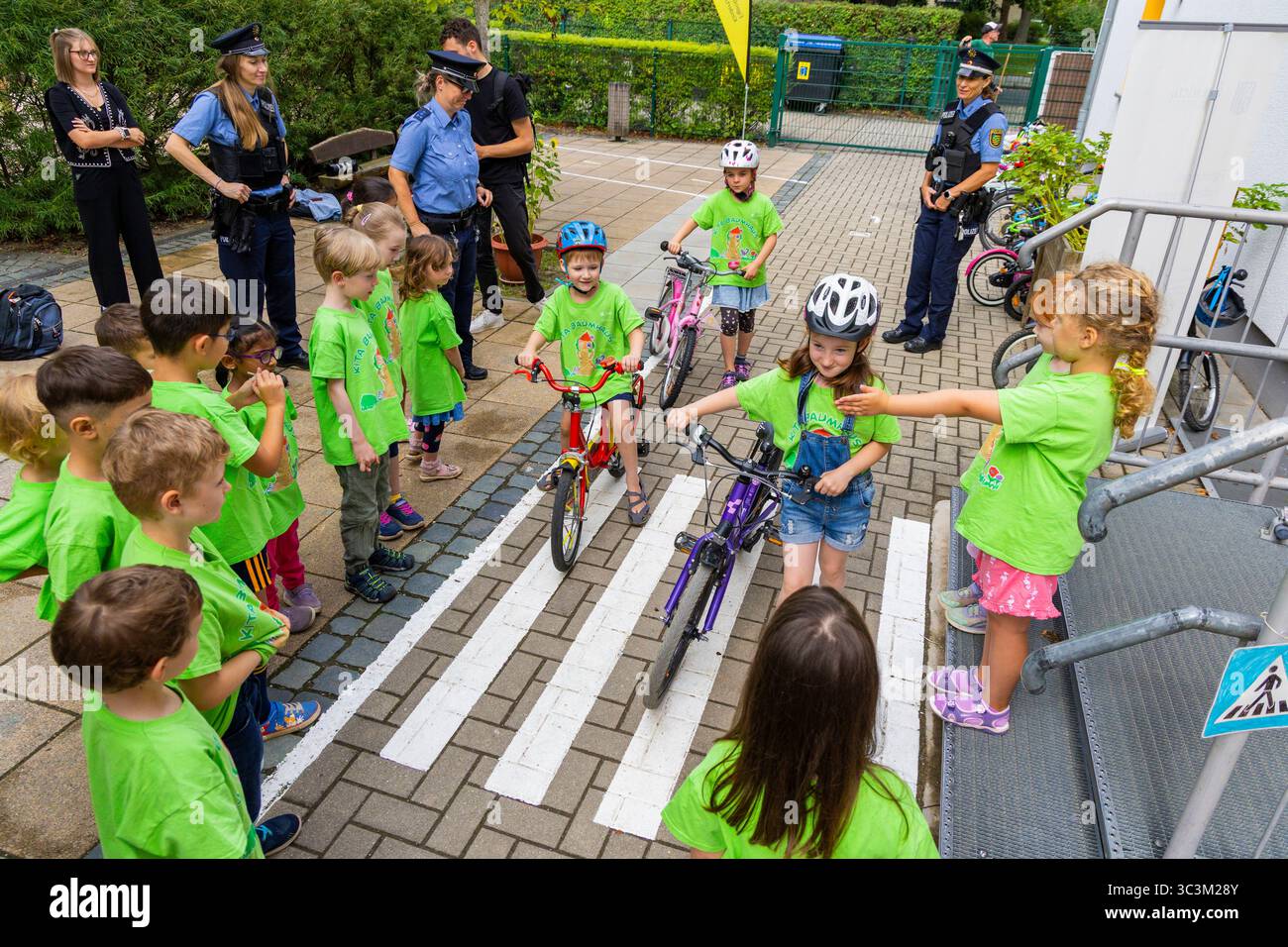 Presse- und Fototermin zur Verkehrssicherheit in der Kita Baumhaus die Dresdner Kita BAUMHAUS mit ihrem naturpädagogischen Schwerpunkt. Die gute Verkehrsanbindung birgt aber zum Teil komplexe Herausforderungen für die künftigen Schulkinder. Durch gezielte Übungen, Rollenspiele und gemeinsame Spaziergänge mit ihren Erzieherinnen und Erziehern können die Kinder ein Gefühl für sichere Verhaltensweisen im Straßenraum entwickeln. Einmal im Jahr bringen Bürgerpolizisten den Vorschulkindern die wichtigsten Verkehrsregeln auf spielerische Weise näher. Die Kinder wurden sensibilisiert, Gefahren m Stockfoto