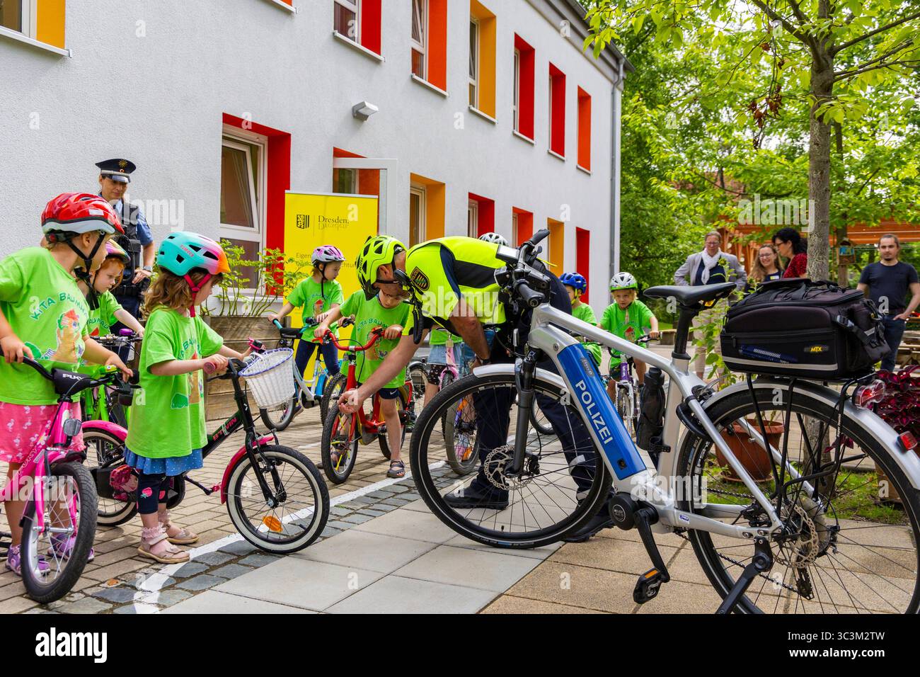 Presse- und Fototermin zur Verkehrssicherheit in der Kita Baumhaus die Dresdner Kita BAUMHAUS mit ihrem naturpädagogischen Schwerpunkt. Die gute Verkehrsanbindung birgt aber zum Teil komplexe Herausforderungen für die künftigen Schulkinder. Durch gezielte Übungen, Rollenspiele und gemeinsame Spaziergänge mit ihren Erzieherinnen und Erziehern können die Kinder ein Gefühl für sichere Verhaltensweisen im Straßenraum entwickeln. Einmal im Jahr bringen Bürgerpolizisten den Vorschulkindern die wichtigsten Verkehrsregeln auf spielerische Weise näher. Die Kinder wurden sensibilisiert, Gefahren m Stockfoto