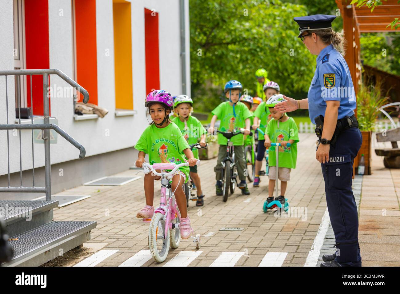 Presse- und Fototermin zur Verkehrssicherheit in der Kita Baumhaus die Dresdner Kita BAUMHAUS mit ihrem naturpädagogischen Schwerpunkt. Die gute Verkehrsanbindung birgt aber zum Teil komplexe Herausforderungen für die künftigen Schulkinder. Durch gezielte Übungen, Rollenspiele und gemeinsame Spaziergänge mit ihren Erzieherinnen und Erziehern können die Kinder ein Gefühl für sichere Verhaltensweisen im Straßenraum entwickeln. Einmal im Jahr bringen Bürgerpolizisten den Vorschulkindern die wichtigsten Verkehrsregeln auf spielerische Weise näher. Die Kinder wurden sensibilisiert, Gefahren m Stockfoto