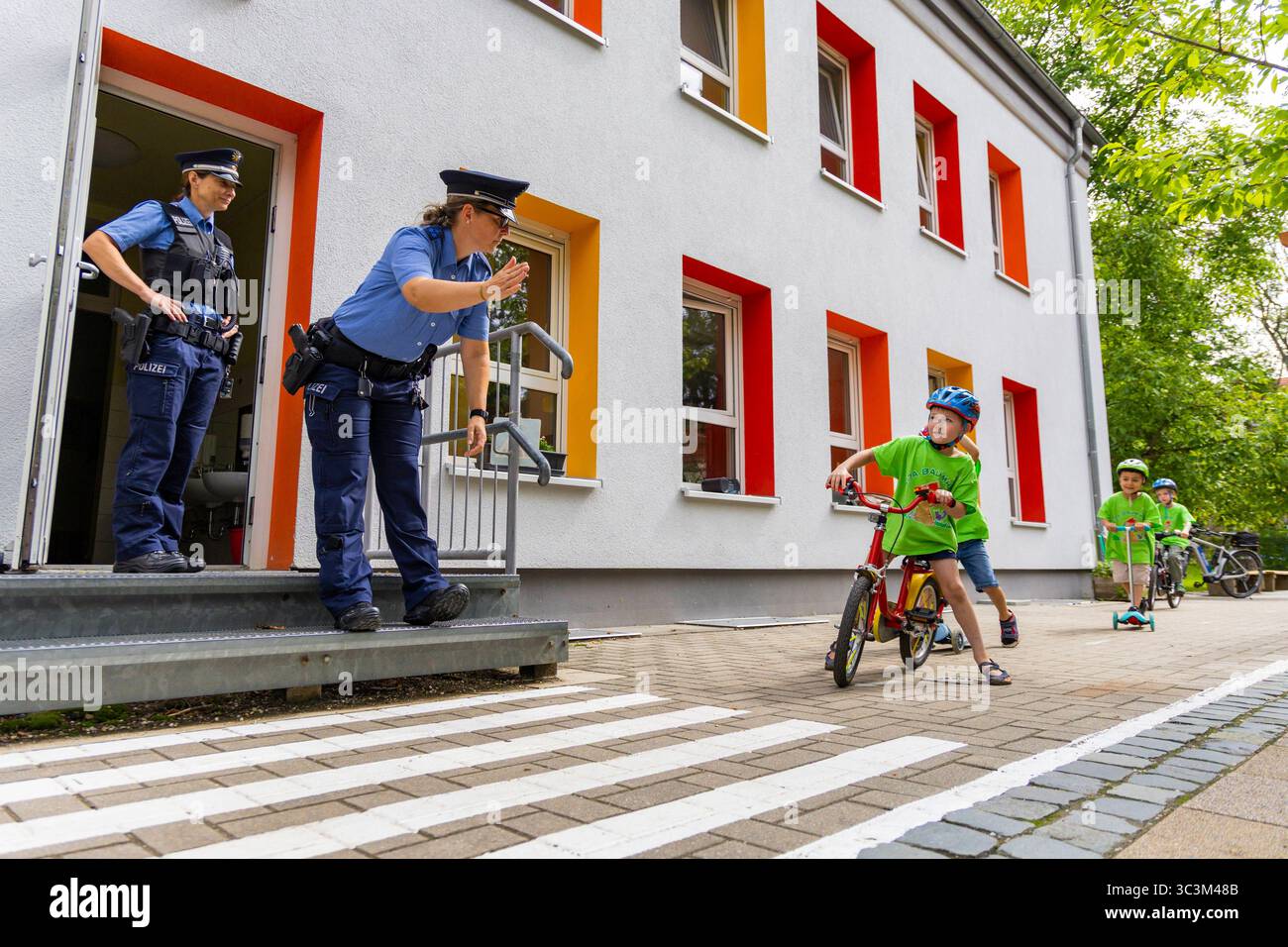 Presse- und Fototermin zur Verkehrssicherheit in der Kita Baumhaus die Dresdner Kita BAUMHAUS mit ihrem naturpädagogischen Schwerpunkt. Die gute Verkehrsanbindung birgt aber zum Teil komplexe Herausforderungen für die künftigen Schulkinder. Durch gezielte Übungen, Rollenspiele und gemeinsame Spaziergänge mit ihren Erzieherinnen und Erziehern können die Kinder ein Gefühl für sichere Verhaltensweisen im Straßenraum entwickeln. Einmal im Jahr bringen Bürgerpolizisten den Vorschulkindern die wichtigsten Verkehrsregeln auf spielerische Weise näher. Die Kinder wurden sensibilisiert, Gefahren m Stockfoto