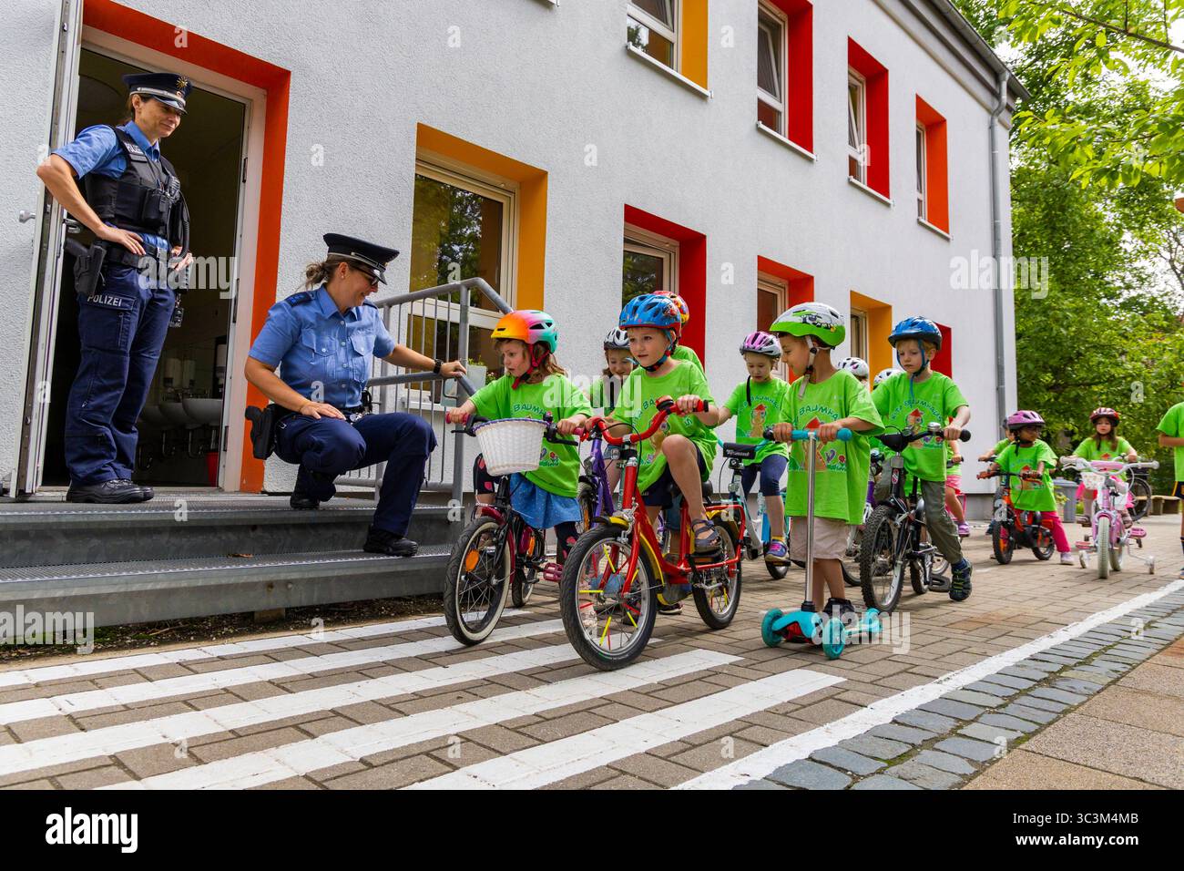Presse- und Fototermin zur Verkehrssicherheit in der Kita Baumhaus die Dresdner Kita BAUMHAUS mit ihrem naturpädagogischen Schwerpunkt. Die gute Verkehrsanbindung birgt aber zum Teil komplexe Herausforderungen für die künftigen Schulkinder. Durch gezielte Übungen, Rollenspiele und gemeinsame Spaziergänge mit ihren Erzieherinnen und Erziehern können die Kinder ein Gefühl für sichere Verhaltensweisen im Straßenraum entwickeln. Einmal im Jahr bringen Bürgerpolizisten den Vorschulkindern die wichtigsten Verkehrsregeln auf spielerische Weise näher. Die Kinder wurden sensibilisiert, Gefahren m Stockfoto