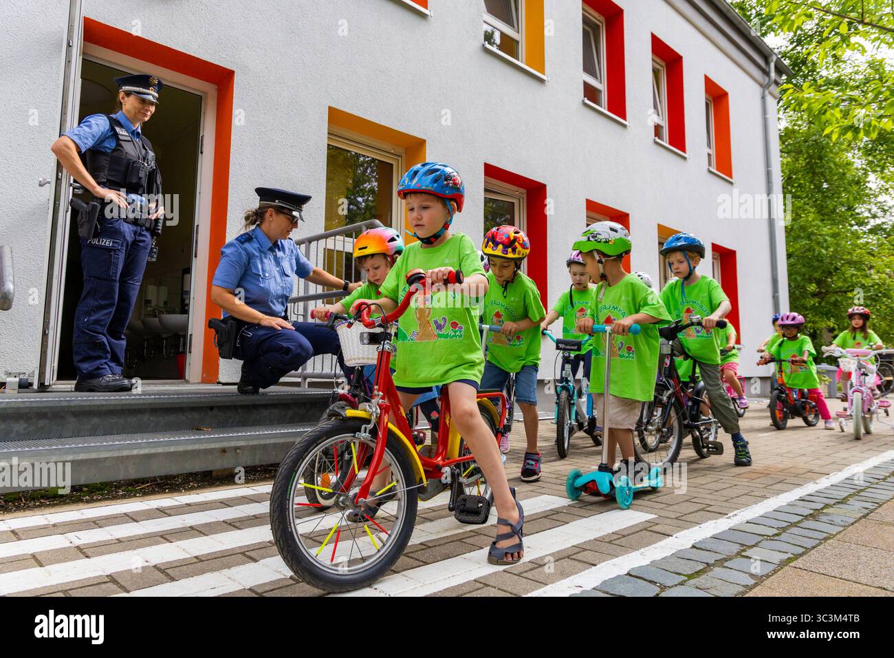 Presse- und Fototermin zur Verkehrssicherheit in der Kita Baumhaus die Dresdner Kita BAUMHAUS mit ihrem naturpädagogischen Schwerpunkt. Die gute Verkehrsanbindung birgt aber zum Teil komplexe Herausforderungen für die künftigen Schulkinder. Durch gezielte Übungen, Rollenspiele und gemeinsame Spaziergänge mit ihren Erzieherinnen und Erziehern können die Kinder ein Gefühl für sichere Verhaltensweisen im Straßenraum entwickeln. Einmal im Jahr bringen Bürgerpolizisten den Vorschulkindern die wichtigsten Verkehrsregeln auf spielerische Weise näher. Die Kinder wurden sensibilisiert, Gefahren m Stockfoto