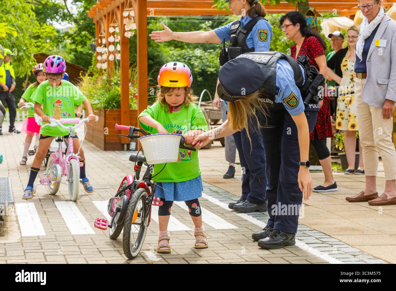 Presse- und Fototermin zur Verkehrssicherheit in der Kita Baumhaus die Dresdner Kita BAUMHAUS mit ihrem naturpädagogischen Schwerpunkt. Die gute Verkehrsanbindung birgt aber zum Teil komplexe Herausforderungen für die künftigen Schulkinder. Durch gezielte Übungen, Rollenspiele und gemeinsame Spaziergänge mit ihren Erzieherinnen und Erziehern können die Kinder ein Gefühl für sichere Verhaltensweisen im Straßenraum entwickeln. Einmal im Jahr bringen Bürgerpolizisten den Vorschulkindern die wichtigsten Verkehrsregeln auf spielerische Weise näher. Die Kinder wurden sensibilisiert, Gefahren m Stockfoto