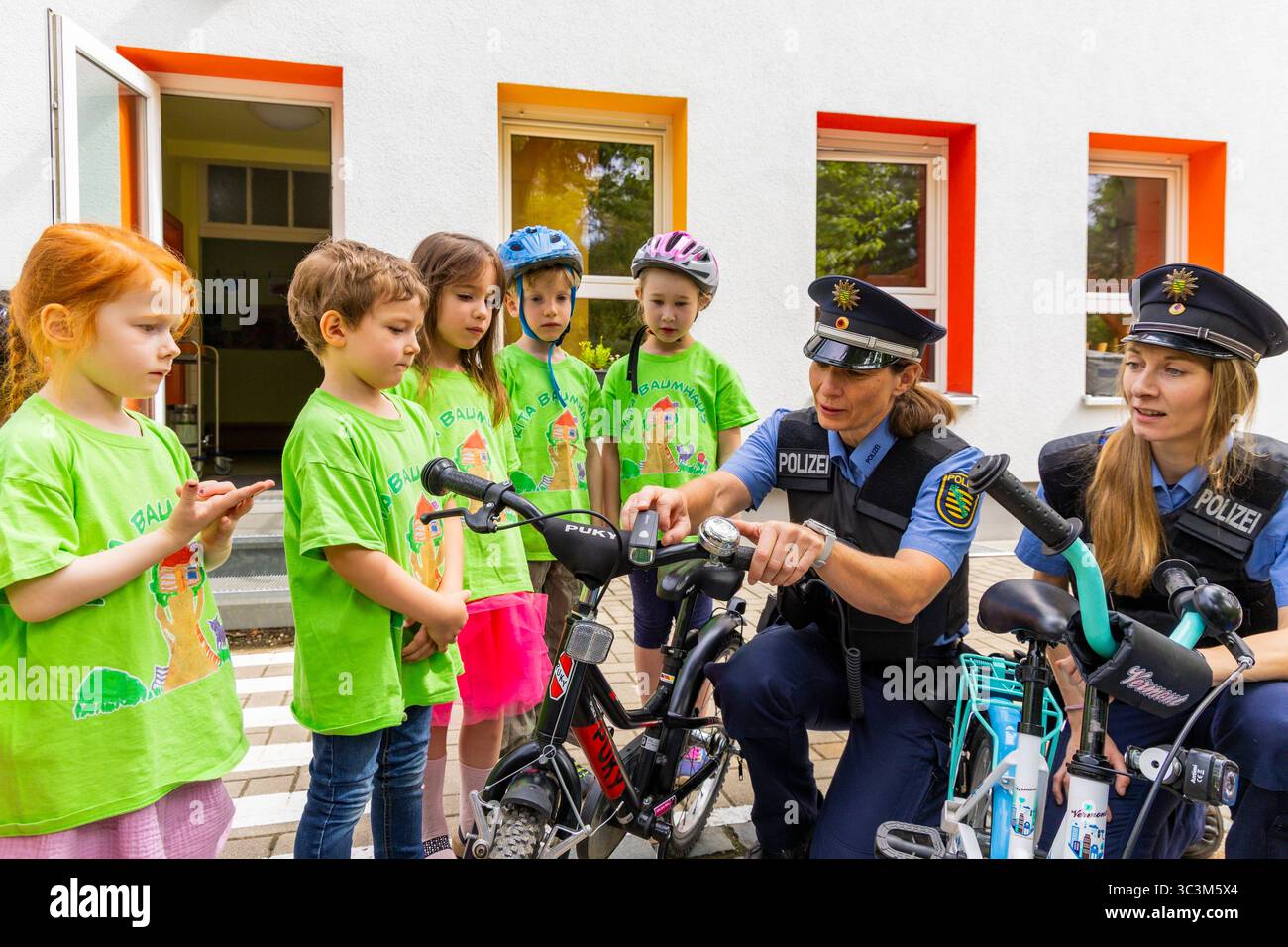 Presse- und Fototermin zur Verkehrssicherheit in der Kita Baumhaus die Dresdner Kita BAUMHAUS mit ihrem naturpädagogischen Schwerpunkt. Die gute Verkehrsanbindung birgt aber zum Teil komplexe Herausforderungen für die künftigen Schulkinder. Durch gezielte Übungen, Rollenspiele und gemeinsame Spaziergänge mit ihren Erzieherinnen und Erziehern können die Kinder ein Gefühl für sichere Verhaltensweisen im Straßenraum entwickeln. Einmal im Jahr bringen Bürgerpolizisten den Vorschulkindern die wichtigsten Verkehrsregeln auf spielerische Weise näher. Die Kinder wurden sensibilisiert, Gefahren m Stockfoto