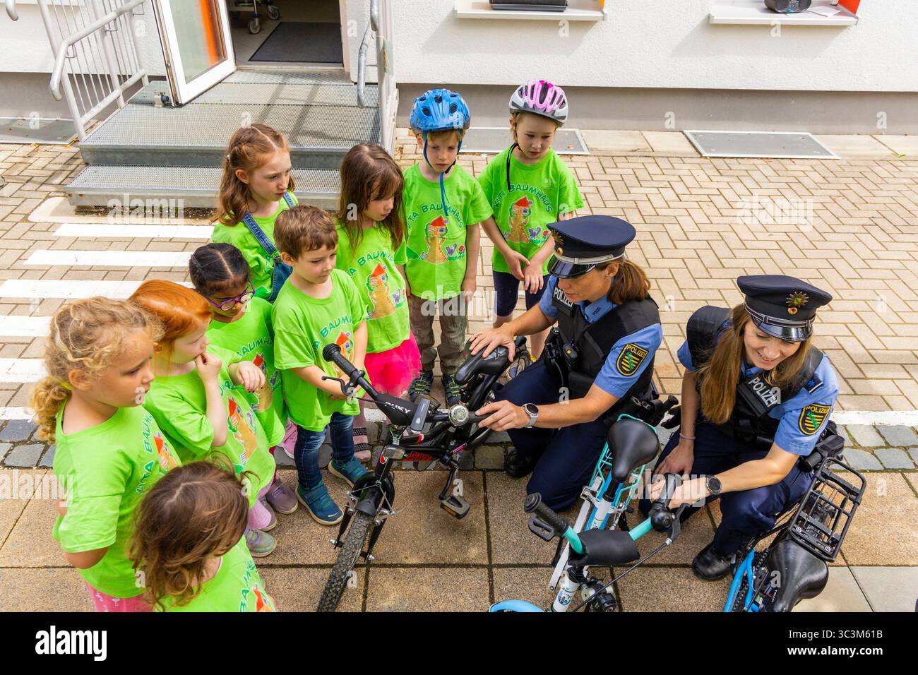 Presse- und Fototermin zur Verkehrssicherheit in der Kita Baumhaus die Dresdner Kita BAUMHAUS mit ihrem naturpädagogischen Schwerpunkt. Die gute Verkehrsanbindung birgt aber zum Teil komplexe Herausforderungen für die künftigen Schulkinder. Durch gezielte Übungen, Rollenspiele und gemeinsame Spaziergänge mit ihren Erzieherinnen und Erziehern können die Kinder ein Gefühl für sichere Verhaltensweisen im Straßenraum entwickeln. Einmal im Jahr bringen Bürgerpolizisten den Vorschulkindern die wichtigsten Verkehrsregeln auf spielerische Weise näher. Die Kinder wurden sensibilisiert, Gefahren m Stockfoto