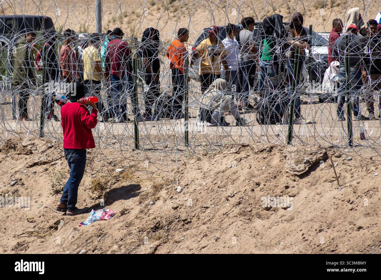 Migranten versammeln sich über einen Stacheldraht in Ciudad Juarez, um die Herausforderungen der Migration hervorzuheben. Stockfoto