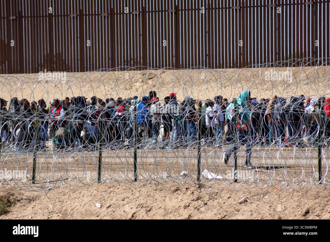 Migranten versammeln sich am Grenzzaun von Ciudad Juarez und zeigen die Herausforderungen der Migration auf. Stockfoto