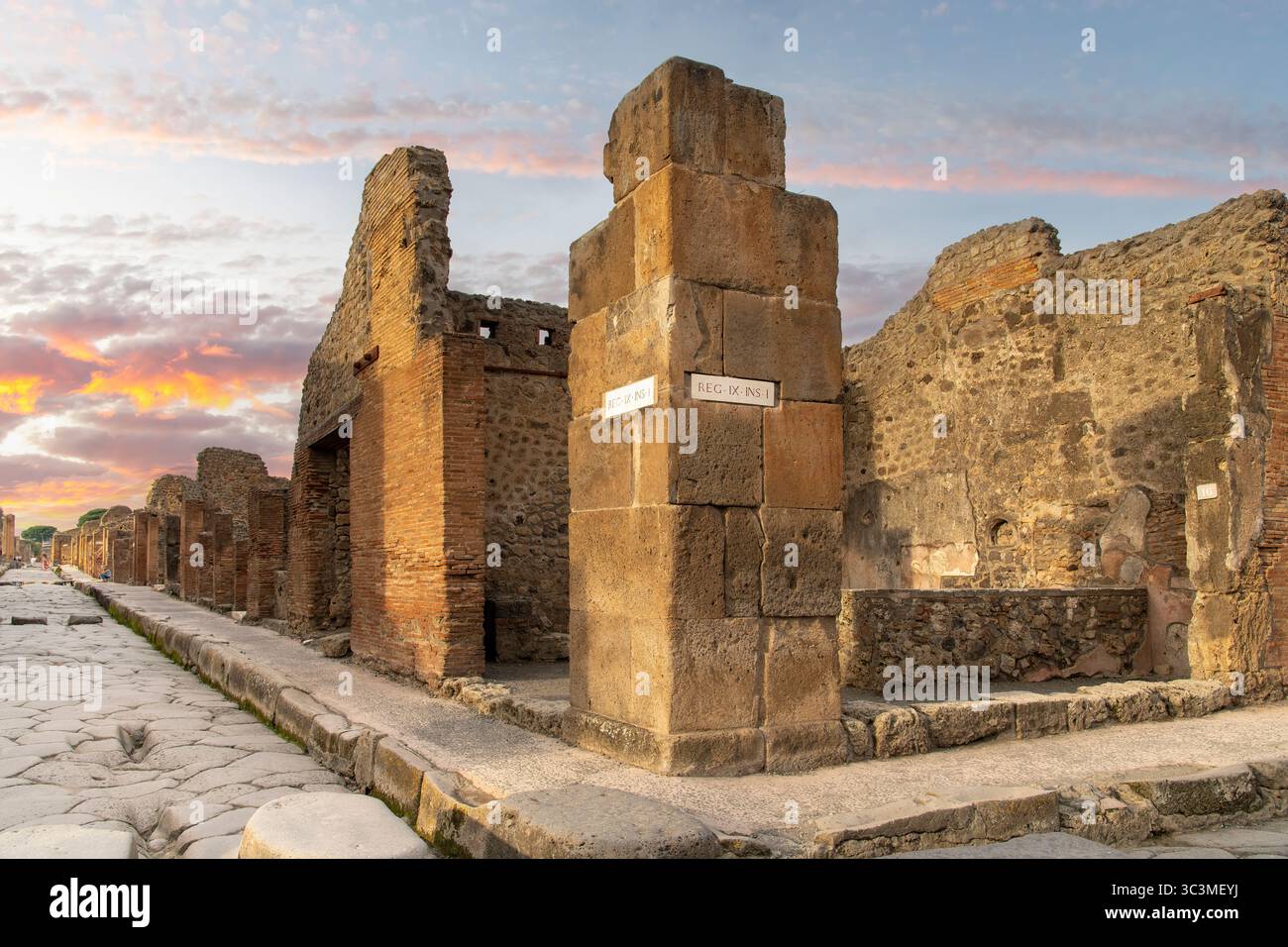 Haus an der Ecke Straße und Straßennamen in lateinischer Sprache während des Sonnenuntergangs in Pompeji in der Nähe von Neapel, Italien, die weitgehend das römische Leben unter der Asche erhalten haben Stockfoto
