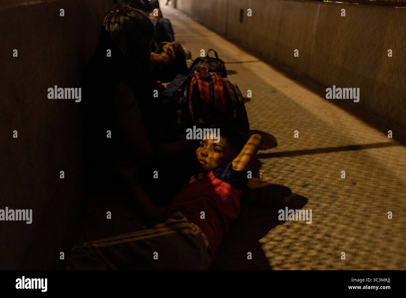 Eine Familie ruht in einer dunklen Unterführung in Ciudad Juarez, die die Herausforderungen der Migranten verdeutlicht. Stockfoto