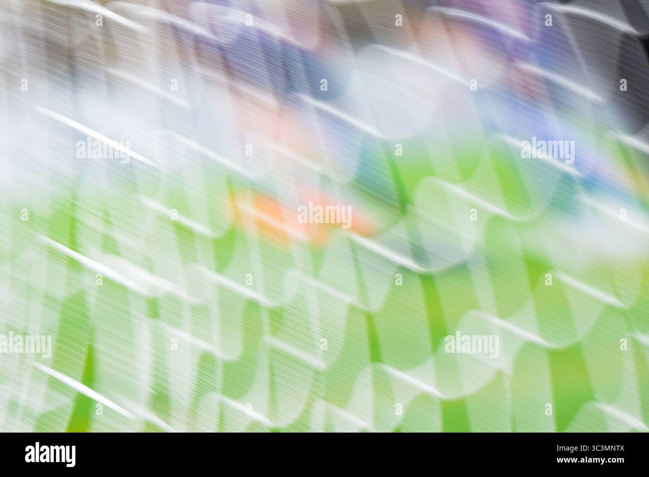 Verschwommenes Bild eines Fußballnetzes unter hellem Sonnenlicht, mit grünem Gras im Hintergrund. Das weiße Netz und das lebendige Feld sorgen für eine dynamische Atmosphäre Stockfoto