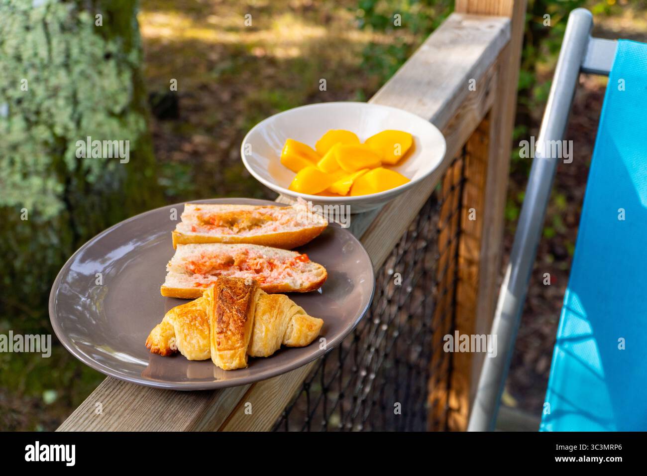 Ein rustikales Frühstück in einer gemütlichen Holzhütte im Wald, mit frischen Croissants, geschnittenem Baguette und reifem Obst, perfekt für Ökotourismus Stockfoto