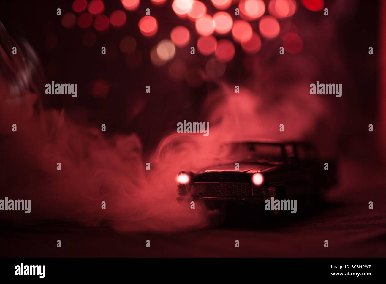 Künstlerisches, stimmungsvolles Foto von zwei dunklen Metallautos, die aus dichtem Nebel auftauchen und von dramatischer roter Beleuchtung beleuchtet werden. Die filmische Atmosphäre weckt Geheimnisse Stockfoto