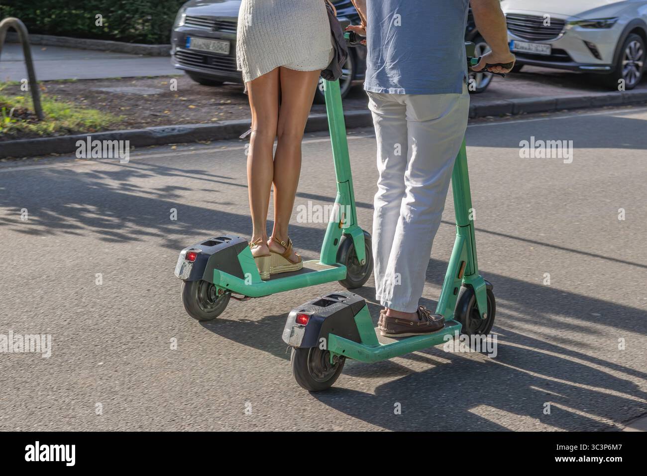 Ein Paar mit Elektrorollern fährt auf der Straße Stockfoto