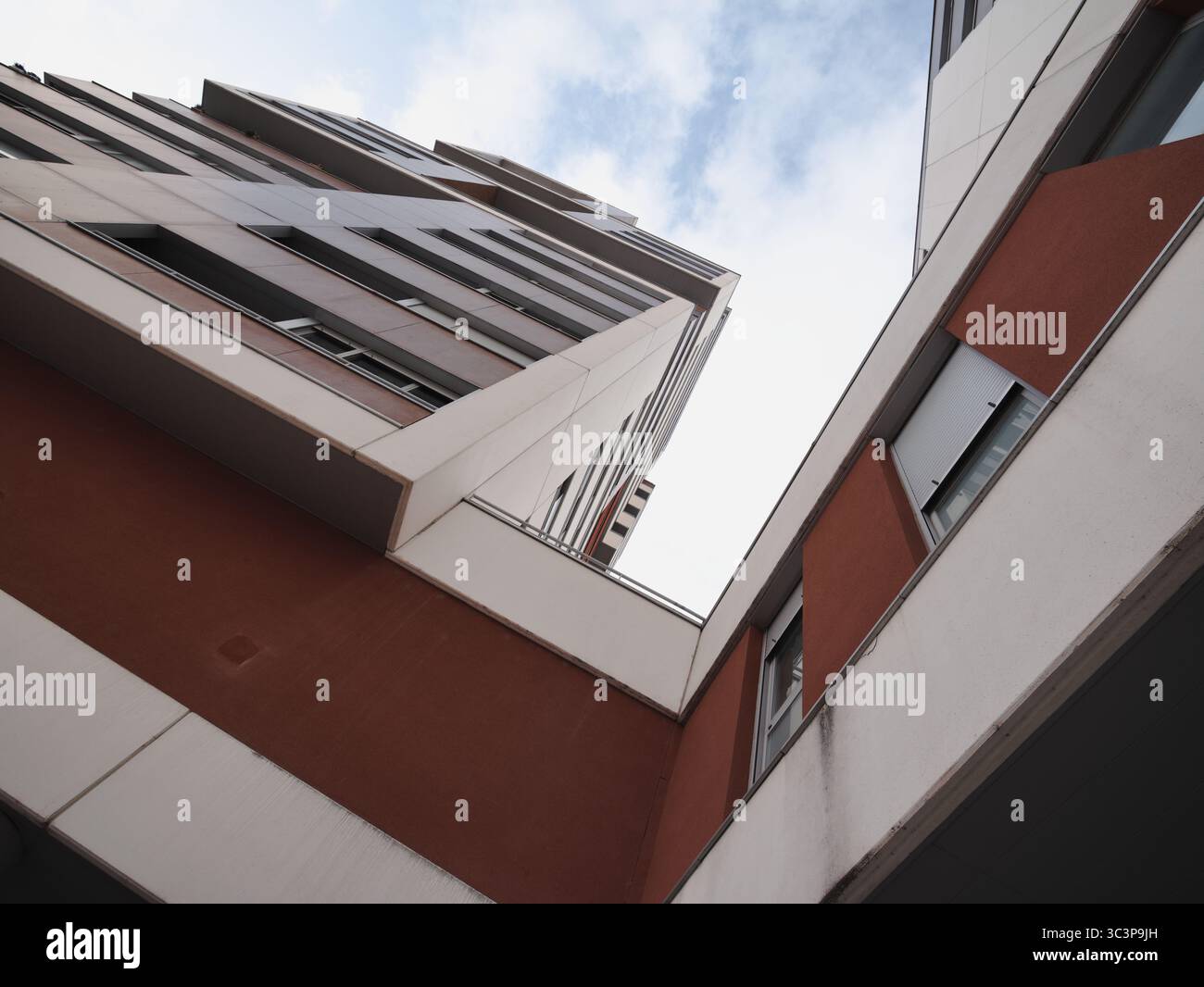Hohe, moderne architektonische Strukturen, von unten aus gesehen, vor der Kulisse des Himmels. Die Gebäude haben geometrische Designs mit einer Mischung aus weißem und rotem PA Stockfoto