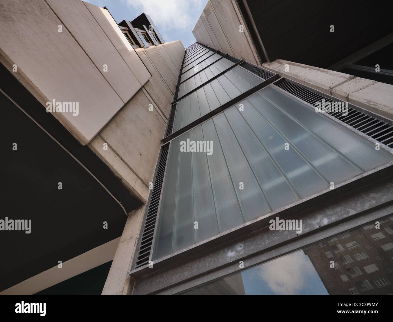 Modernes Wohngebäude in minimalistischem Design mit großen vertikal verlaufenden Glaspaneelen. Die Fassade besteht aus elegantem, mattiertem Glas Stockfoto