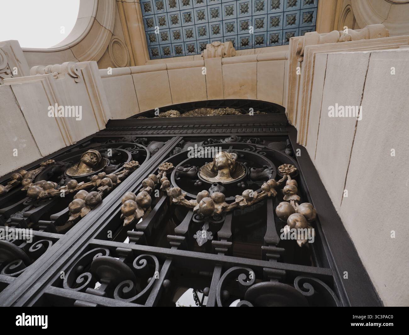 Nahaufnahme einer schwarzen Tür im Renaissance-Stil mit goldenen Verzierungen, in der wir einige Figuren und dekorative Dekorationen sehen können, auch die Decke Stockfoto