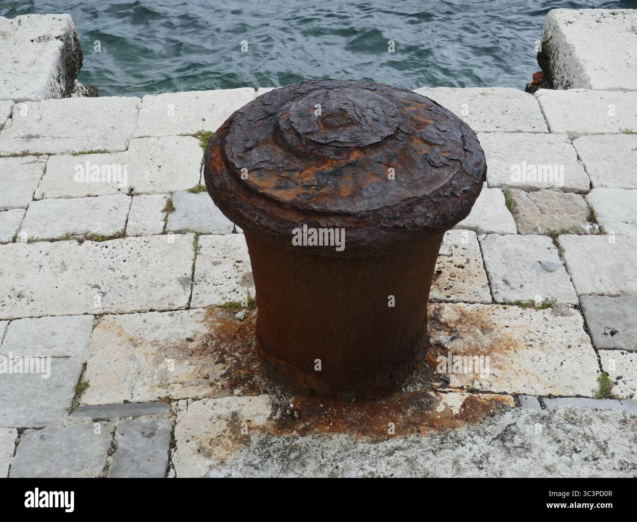 Rostiger alter Metallanker auf dem Steindock am Meer Stockfoto