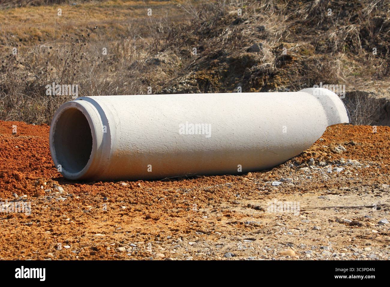 Ein großer Abschnitt aus Betonfertigteilen liegt auf rötlicher Erde, der für die unterirdische Wasserwirtschaft oder Abwasser als Teil eines größeren Standorts bestimmt ist Stockfoto
