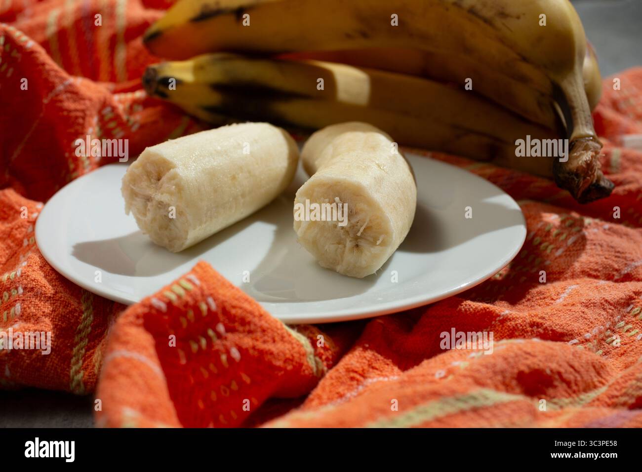 Ein Blick auf eine zerbrochene Banane auf einem Teller, in einem Stillleben. Stockfoto