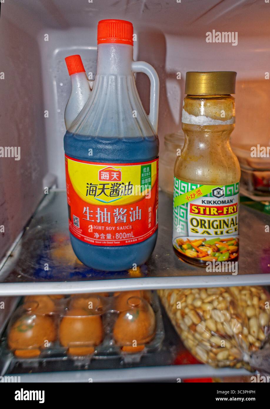 Chinesische leichte Sojasauce in Plastikflasche mit Auslauf neben kommerzieller US-amerikanischer Rührbraten-Sauce, eine aus einem chinesischen Geschäft und eine andere aus den USA importiert Stockfoto