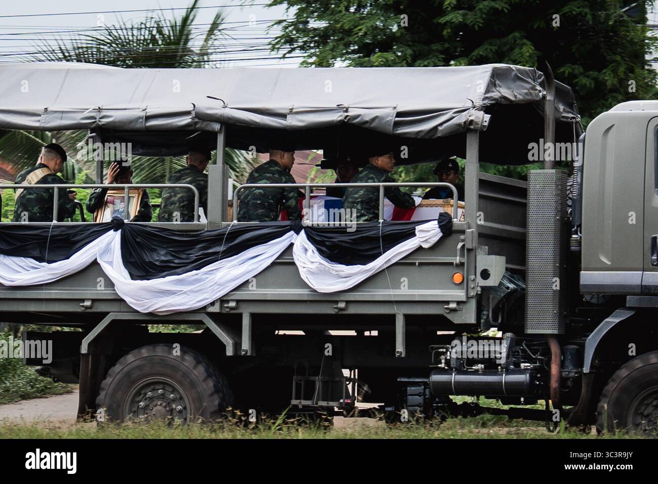 In schwarz-weißem Tuch gehüllt, transportiert ein thailändischer Militärwagen die Leiche eines Soldaten, der vermutlich Sergeant Major Thawatchai Busapa ist. Die Spannungen eskalieren entlang der thailändisch-kambodschanischen Grenze, da die militärischen Aktivitäten im Bezirk Kantharalak, Provinz Sisaket, zunehmen. Nur wenige Kilometer von der umstrittenen Grenze entfernt, wurde das Gebiet von Artillerieschuss und verstärkten Truppenbewegungen betroffen. Die erneute Eskalation, die in langjährigen territorialen Streitigkeiten und jüngsten Anschuldigungen des Landmineneinsatzes begründet ist, hat bei der örtlichen Zivilbevölkerung Ängste ausgelöst, was zu Evakuierungen und einem erhöhten Zustand von A geführt hat Stockfoto
