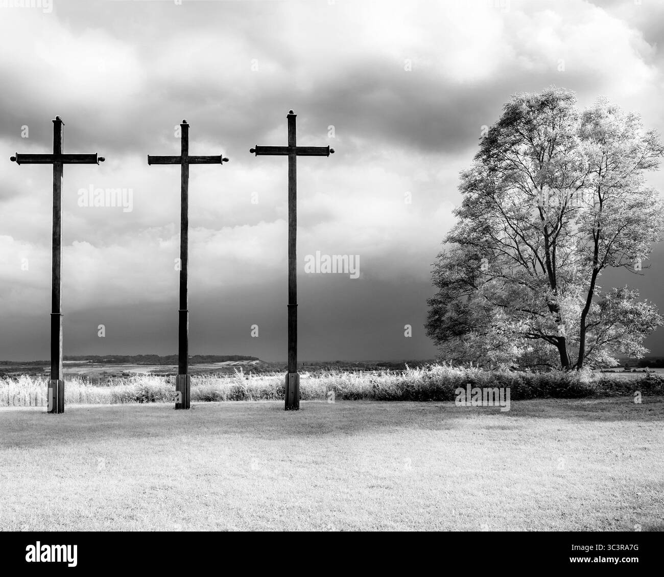 Drei hölzerne Kreuze gegen einen stürmischen Himmel. Schwarzweißfoto Stockfoto