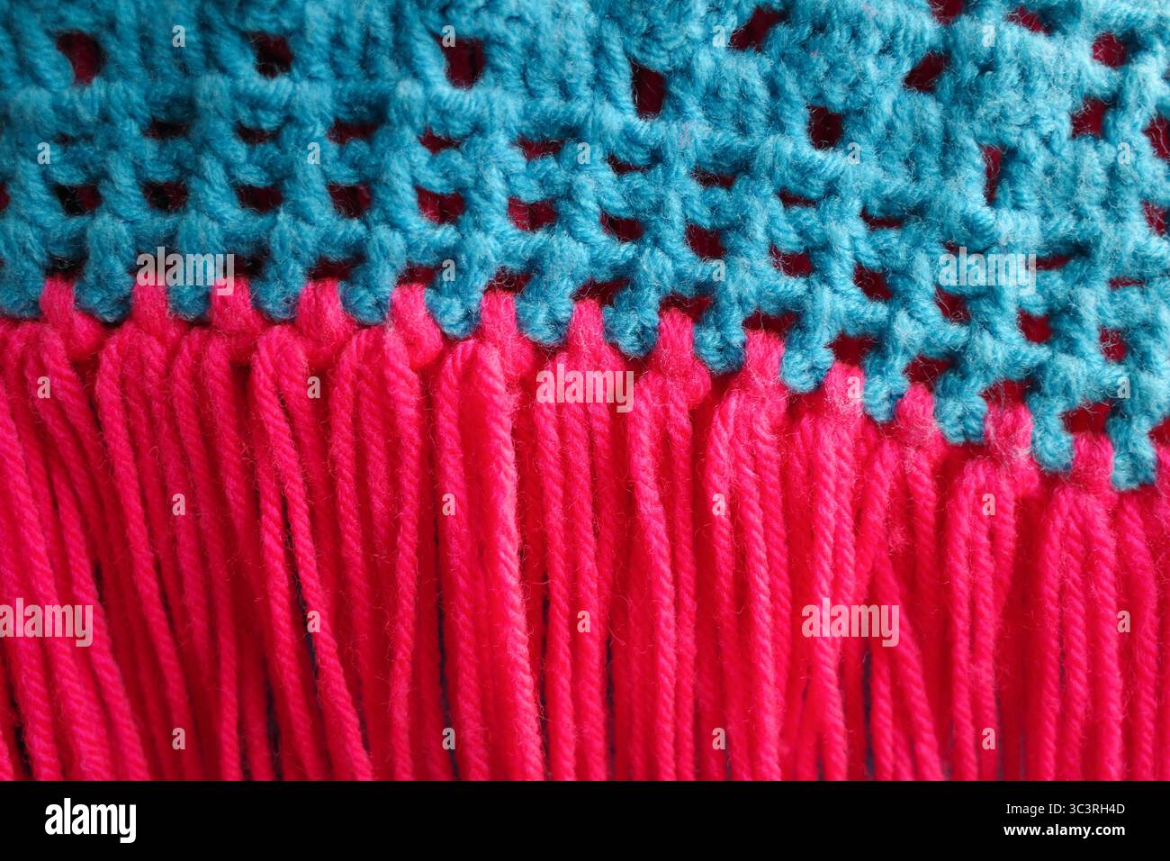Nahaufnahme strukturiert aus einem leuchtend blauen und rosa Häkel- oder Strickstoff. Stockfoto