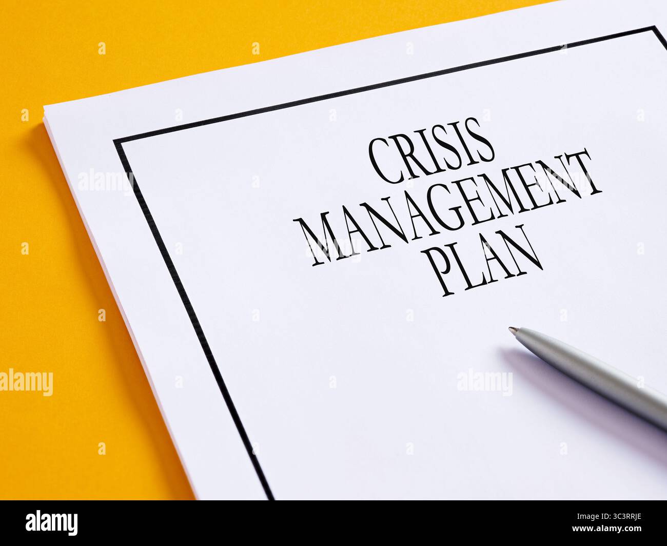 Konzept des Wirtschaftskrisenmanagements. Der Krisenmanagementplan liegt auf einer gelben Oberfläche, auf der ein Stift aufliegt. Stockfoto