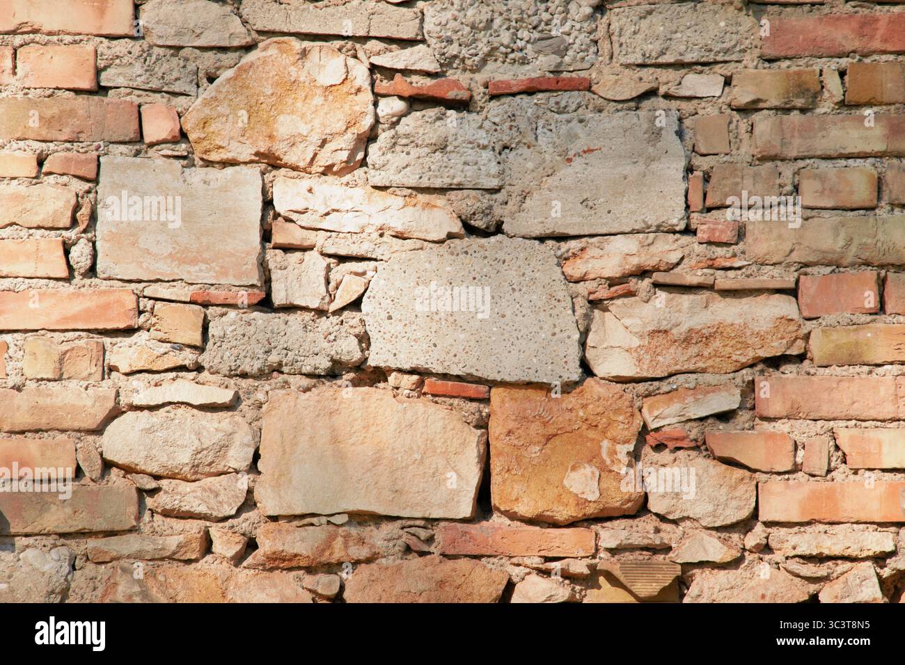 Alte Steinmauer mit rauer, verwitterter Oberfläche und unregelmäßigen Steinen, die Alter und natürliche Textur in Nahaufnahme zeigen. Stockfoto