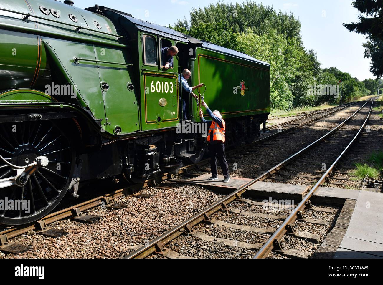 Die Flying Scotsman Dampflokomotive Feuerwehrmann und der Hampton Loade Signalgeber tauschen ihre Instrumente aus, wenn der Zug durch den Bahnhof Hampton Loade fährt Stockfoto