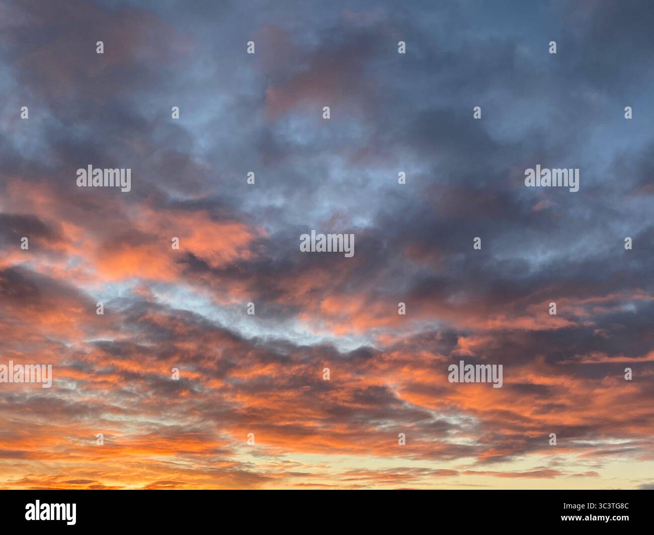 Der Himmel entzündet sich mit leuchtenden Farben, während die Sonne unter dem Horizont untergeht, ein wunderschöner Sonnenuntergang. Stockfoto