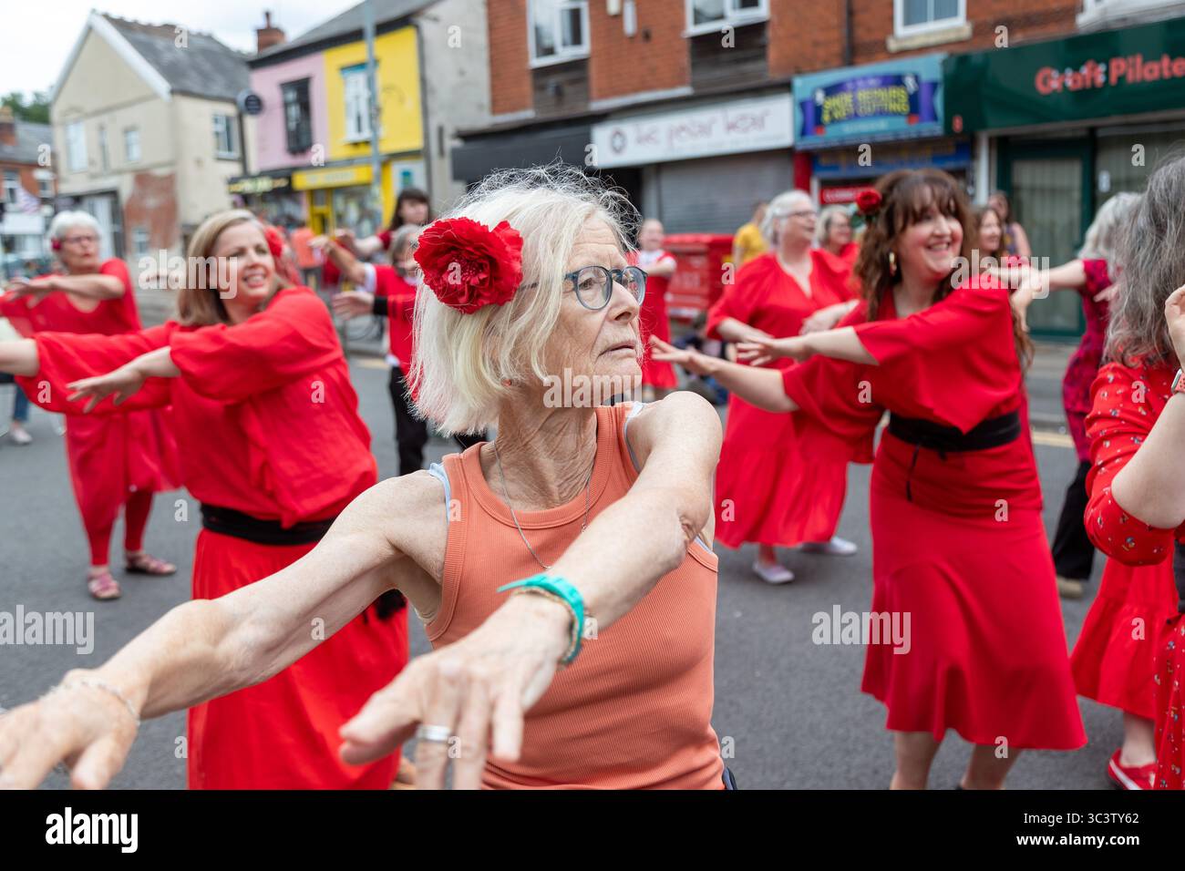 Birmingham, Großbritannien. Juli 2025. 300 Menschen treffen sich zusammen, um eine Tanzroutine namens Most Wuthering Heights Ever in Kings Heath, Birmingham, Großbritannien, aufzuführen. Die Teilnehmer, alle in rot gekleidet, wurden von Jess Phillips, Labour-Abgeordneter für Yardley, Birmingham, angesprochen, bevor sie das Musikvideo für Kate Bushs ikonisches Lied „Wuthering Heights“ reproduzierten. Die Veranstaltung sammelt Gelder für Women's Empowerment and Recovery Educators und ANAWIM Charitations. Quelle: Peter Lopeman/Alamy Live News Stockfoto