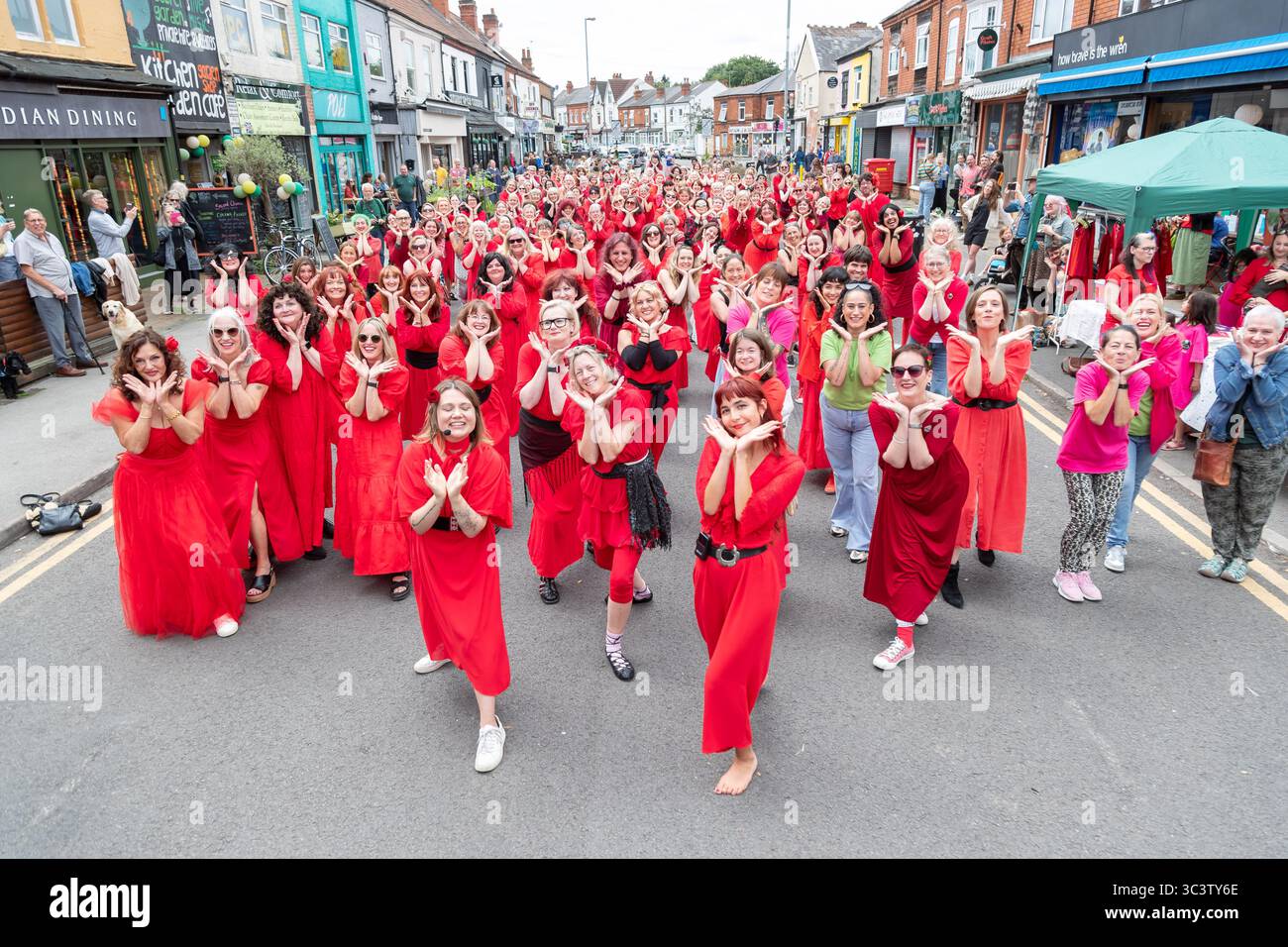 Birmingham, Großbritannien. Juli 2025. 300 Menschen treffen sich zusammen, um eine Tanzroutine namens Most Wuthering Heights Ever in Kings Heath, Birmingham, Großbritannien, aufzuführen. Die Teilnehmer, alle in rot gekleidet, wurden von Jess Phillips, Labour-Abgeordneter für Yardley, Birmingham, angesprochen, bevor sie das Musikvideo für Kate Bushs ikonisches Lied „Wuthering Heights“ reproduzierten. Die Veranstaltung sammelt Gelder für Women's Empowerment and Recovery Educators und ANAWIM Charitations. Quelle: Peter Lopeman/Alamy Live News Stockfoto