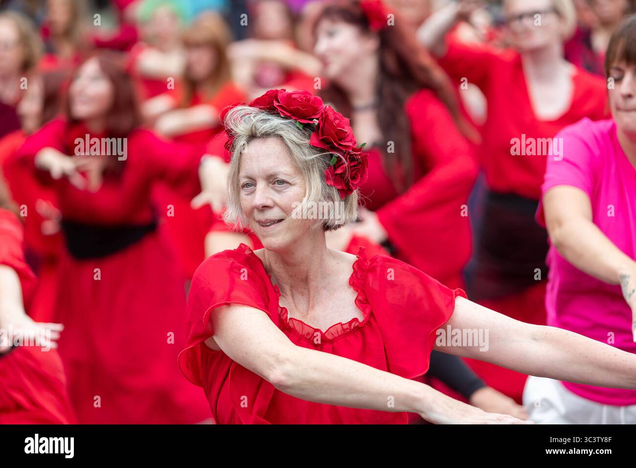 Birmingham, Großbritannien. Juli 2025. 300 Menschen treffen sich zusammen, um eine Tanzroutine namens Most Wuthering Heights Ever in Kings Heath, Birmingham, Großbritannien, aufzuführen. Die Teilnehmer, alle in rot gekleidet, wurden von Jess Phillips, Labour-Abgeordneter für Yardley, Birmingham, angesprochen, bevor sie das Musikvideo für Kate Bushs ikonisches Lied „Wuthering Heights“ reproduzierten. Die Veranstaltung sammelt Gelder für Women's Empowerment and Recovery Educators und ANAWIM Charitations. Quelle: Peter Lopeman/Alamy Live News Stockfoto