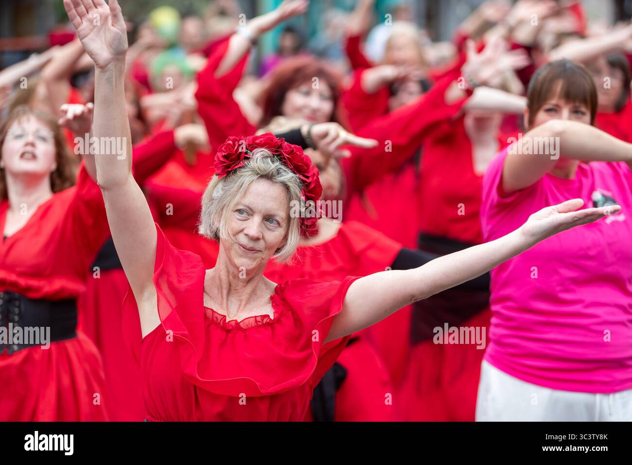 Birmingham, Großbritannien. Juli 2025. 300 Menschen treffen sich zusammen, um eine Tanzroutine namens Most Wuthering Heights Ever in Kings Heath, Birmingham, Großbritannien, aufzuführen. Die Teilnehmer, alle in rot gekleidet, wurden von Jess Phillips, Labour-Abgeordneter für Yardley, Birmingham, angesprochen, bevor sie das Musikvideo für Kate Bushs ikonisches Lied „Wuthering Heights“ reproduzierten. Die Veranstaltung sammelt Gelder für Women's Empowerment and Recovery Educators und ANAWIM Charitations. Quelle: Peter Lopeman/Alamy Live News Stockfoto