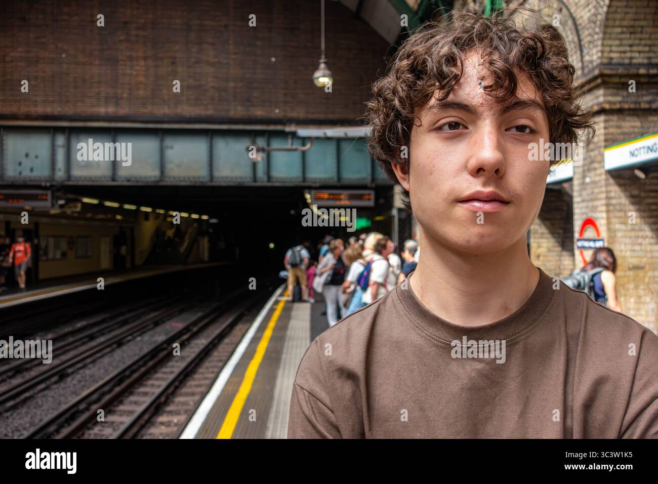 Porträt eines Teenagers gemischter weißer englischer und asiatischer Herkunft, der auf einen Zug an der Londoner U-Bahn-Station Notting Hill Gate wartet Stockfoto