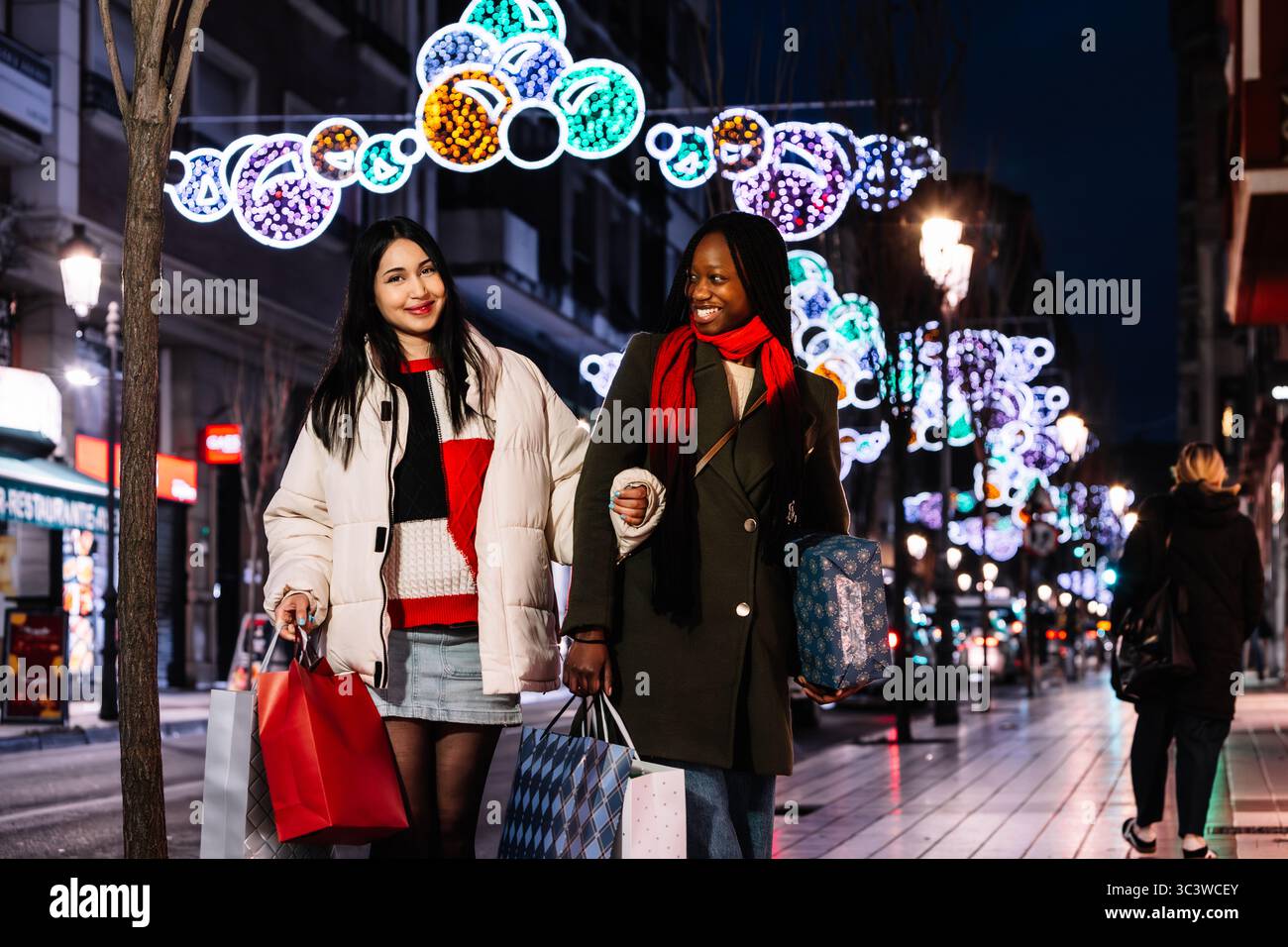 Junge Frauen, die auf der beleuchteten Stadtstraße Urlaub machen. Weihnachten. Feiern. Stockfoto