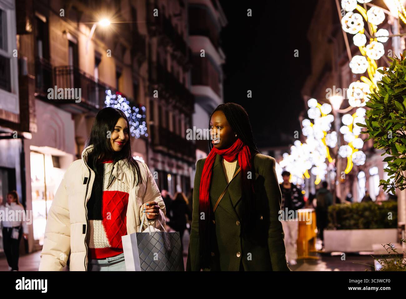 Freunde, die während der Feiertagsnacht durch die festliche Stadtstraße laufen. Weihnachten. Feiern. Stockfoto