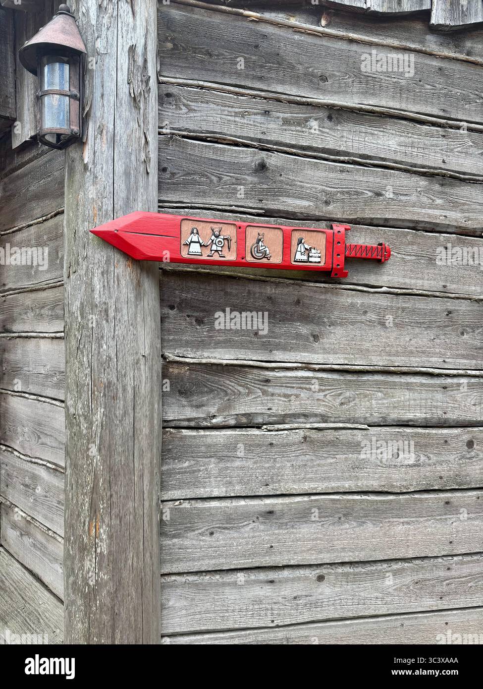 Rotes Richtungsschild an einer rustikalen Holzwand im Hansa Park, Deutschland, das Einrichtungen wie Wickelbereich, erste Hilfe, Toiletten, - Smartphone-aufgenommenes Stockfoto