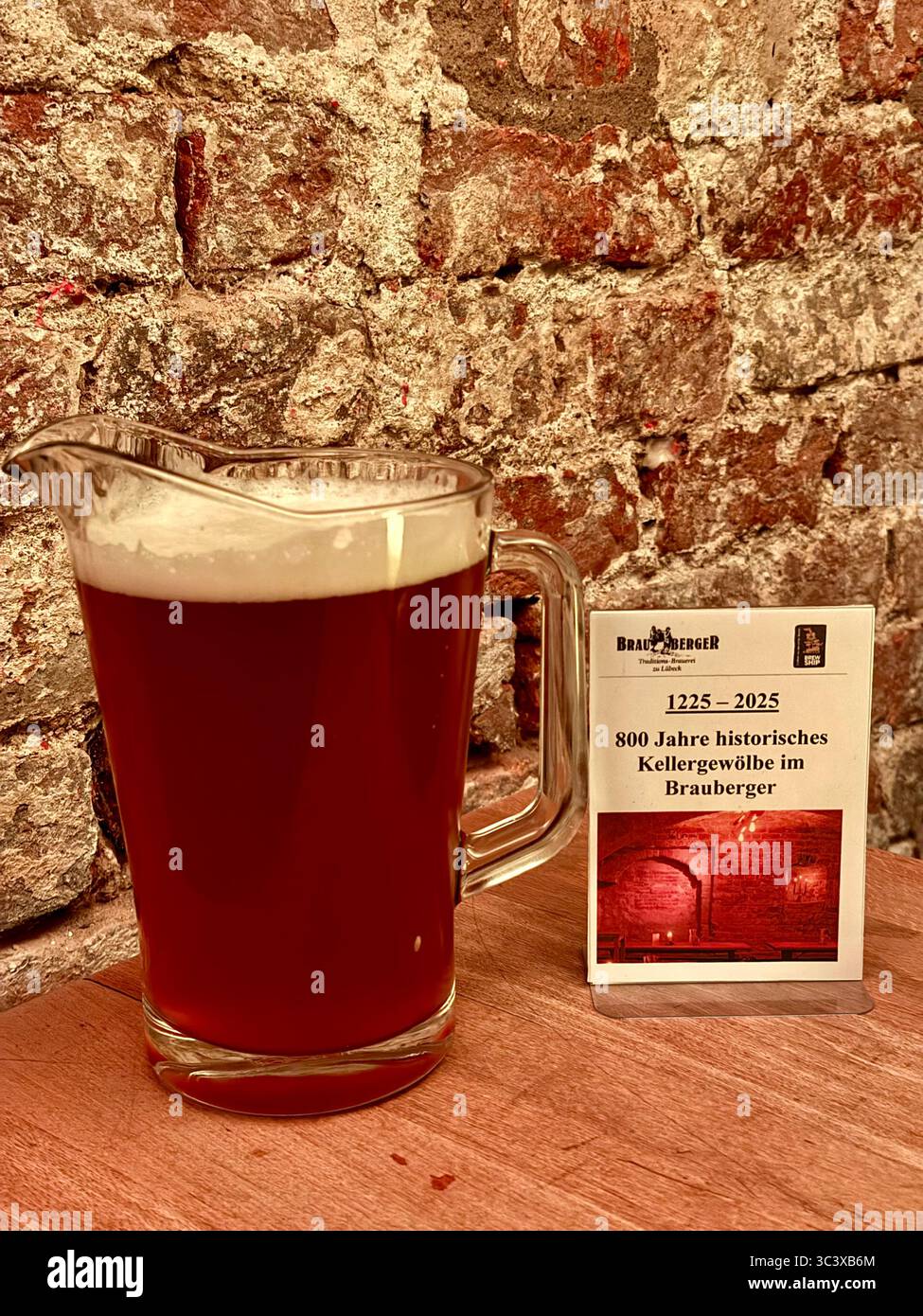 Krug mit Brauberger Bier und Gedenkschild für 800 Jahre historische Kellergewölbe in Lübeck. Stockfoto