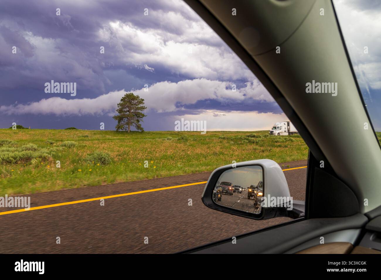 Stürmischer Himmel und malerische ländliche Landschaft im Autofenster, mit Autos im Spiegel Stockfoto